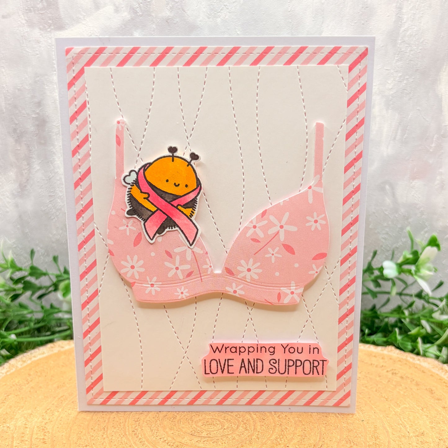 Card with a bra design and a bee wearing a pink ribbon, on a white background with pink and white striped border. Breast Cancer Awareness Bee & Bra Handmade Support Card