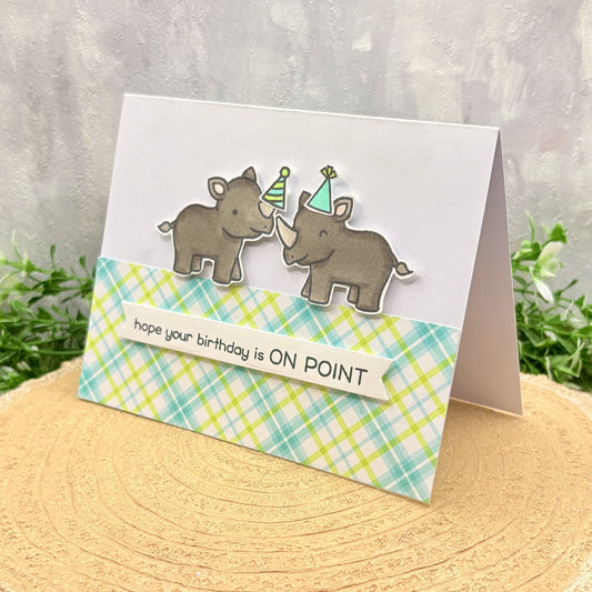 Greeting card with rhino illustrations and text 'hope your birthday is ON POINT' on a textured surface.