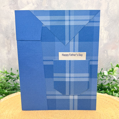 Blue plaid Father's Day card on a textured surface with grass in the background
