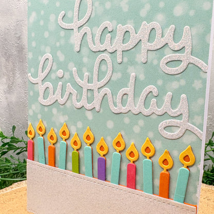Birthday card with colorful candles and 'happy birthday' text on a light blue background.