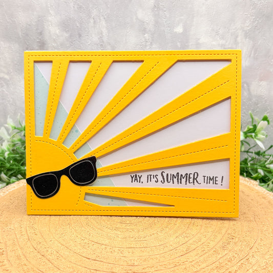 Card with yellow sun design and sunglasses, featuring 'Yay, it's Summer time!' text on a textured surface.