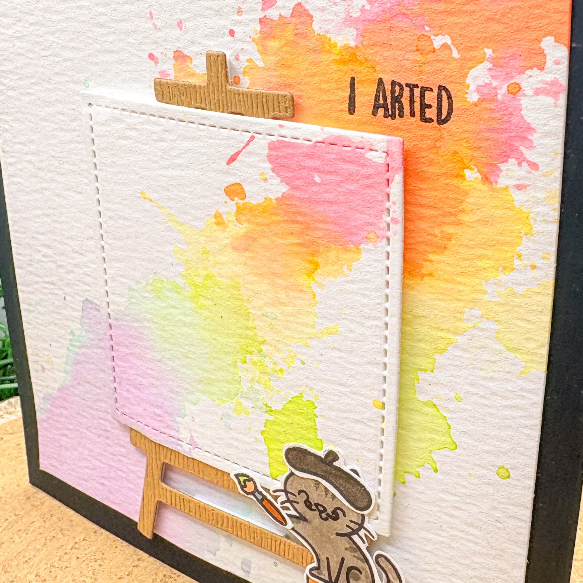 Colorful watercolor splashes with a small figure and 'I Arted' text on a textured background.